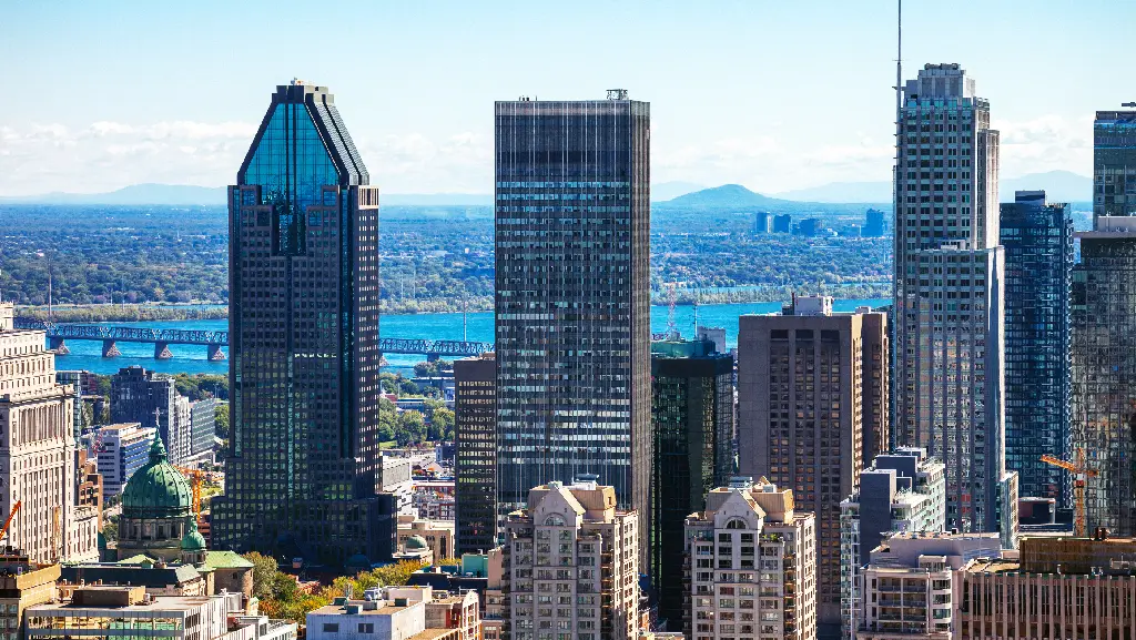 Horizon du centre-ville de Montréal avec ses tours de bureaux modernes et le fleuve Saint-Laurent en arrière-plan par temps clair.