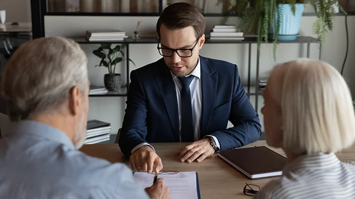 avocat rencontrant deux clients seniors dans un bureau pour examiner des documents juridiques et leur fournir des conseils professionnels.
